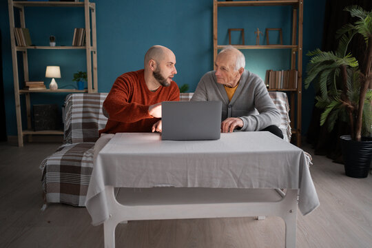 family time home concept. old father and adult son using laptop computer in living room