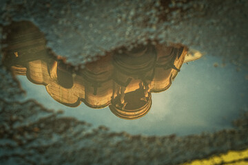 Ornate building reflected upside down in a puddle.