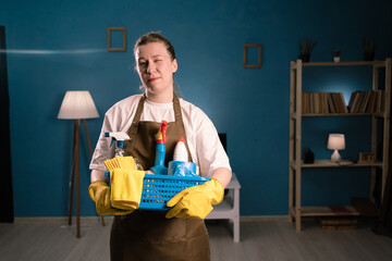 Cleaning service concept. woman cleaner in apron with detergents winking playful or flirting. Female janitor or housewife ready for spring cleaning