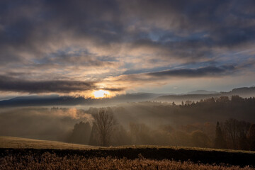 Obraz premium Lever de rayons de soleil sur un paysage brumeux 