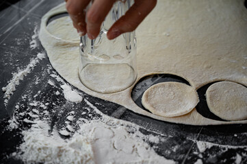 Cutting dough circles with a glass for dumpling preparation