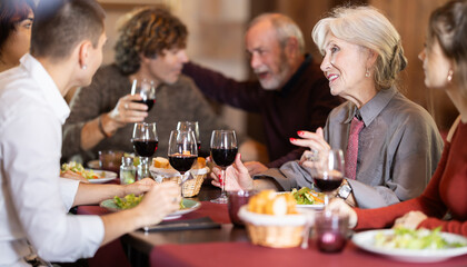 Family celebration. Multinational family eats in restaurant, socializes, drinks wine. Family holiday is excuse to meet.