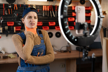 Repairman or Handyman blogger streaming in workshop with assortment tools use smartphone, has Sore...