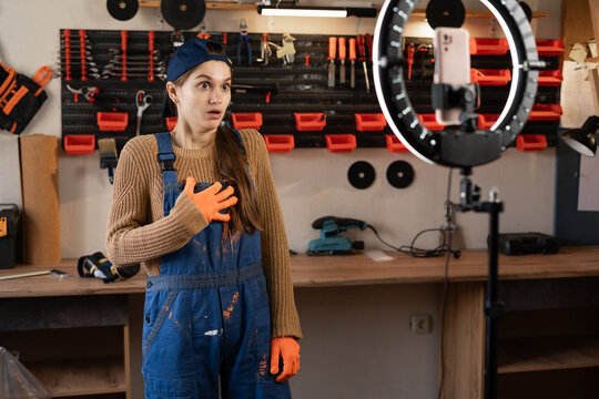 Shocked Repairman or Handyman blogger streaming in workshop with assortment tools using smartphone with omg expression. Blogging, industry and technology - Powered by Adobe