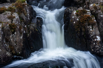 Long-exposure view of water rushing through a narrow rocky gorge with smooth flowing textures