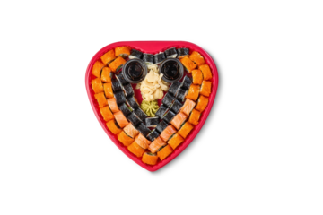 Sushi set with various rolls arranged in a heart shape on a white background