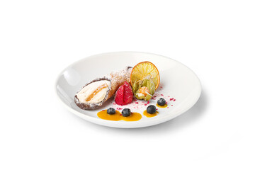 Italian cannoli filled with cream, served on a white plate with berries and citrus