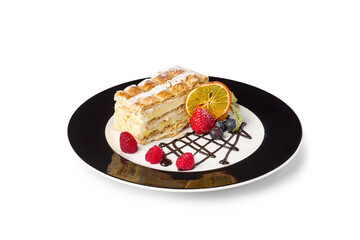 Decorative mille-feuille pastry serving on a plate with fresh berries and orange slice