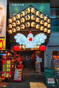 osaka, Namba Sennichimae - dec 7 2025: Vibrant night facade of Japanese restaurant Yakitori Jiro, attracting tourists with its giant illuminated chicken lantern and traditional chochin paper lanterns.