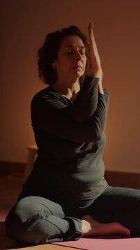 Mature woman sitting on yoga mat practicing meditation and wellness