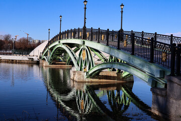 A close-up of an openwork bridge over a lake and its reflection