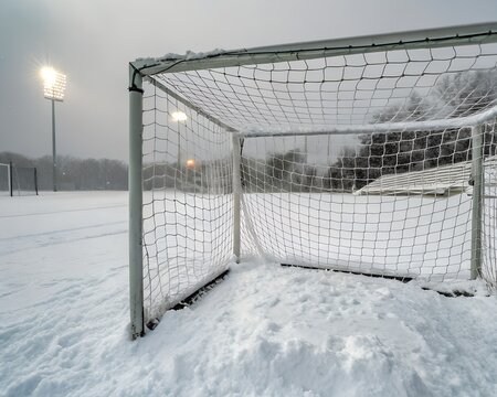 Empty soccer goal on a snow-covered field under stadium lights. - Powered by Adobe
