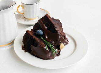 CHOCOLATE CAKE WITH CHOCOLATE FOUNTAIN.  A piece of delicious sponge cake ( brownie ) decorated fresh blueberry and green rosemary twig 
