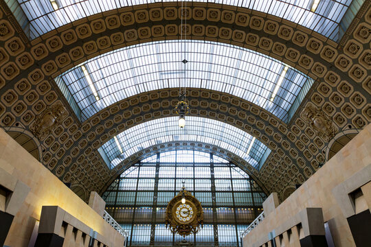 Low angle symmetric interior view of the main hall of the 1900 former Gare d&rsquo;Orsay, now the d&rsquo;Orsay Museum&rsquo;s  glass roof and clock, Paris, France 
