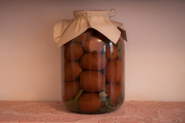 Glass jar with pickled tomatoes sealed with paper cover