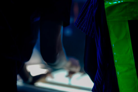 A close up of engineers reviewing a CAD blueprint on a light table. The team is in a smart factory SOC, analyzing an AI automation system and using a radio. - Powered by Adobe