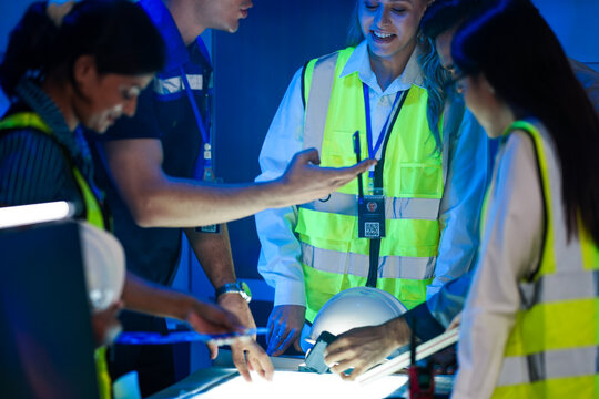 A happy logistics team reviews a successful plan. The diverse group discusses an AI strategy for smart factory optimization, efficiency, and sustainable (ESG) goals.