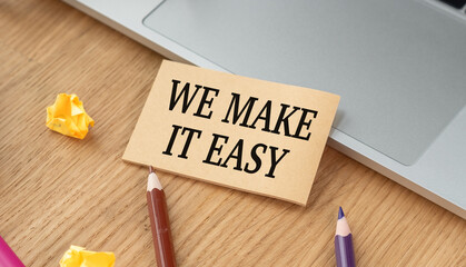 Fototapeta premium A sign that says We Make it Easy is on a desk with a laptop