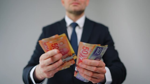 Formally dressed man is counting Canadian Dollar bills, close-up.