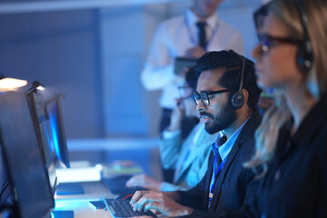 Command center lead focused intense monitoring critical systems late night headset connects team analyzing real time data screen crucial vigilance protects infrastructure operation underway now execut