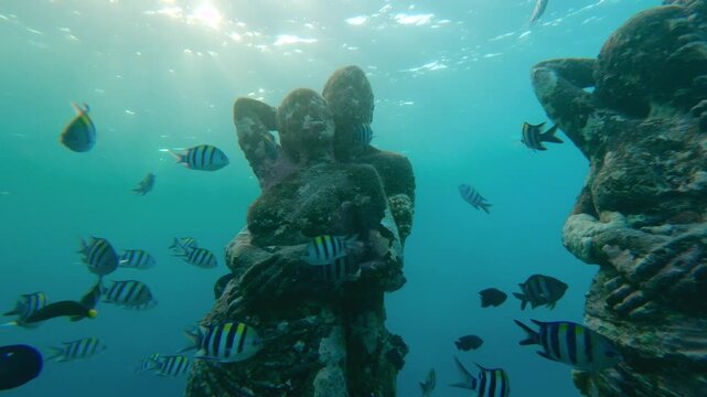 Underwater statues at Gili Meno, Indonesia, surrounded by tropical fish and coral in clear ocean. Famous snorkeling and diving site in Asia, combining marine life, art, and exotic travel.