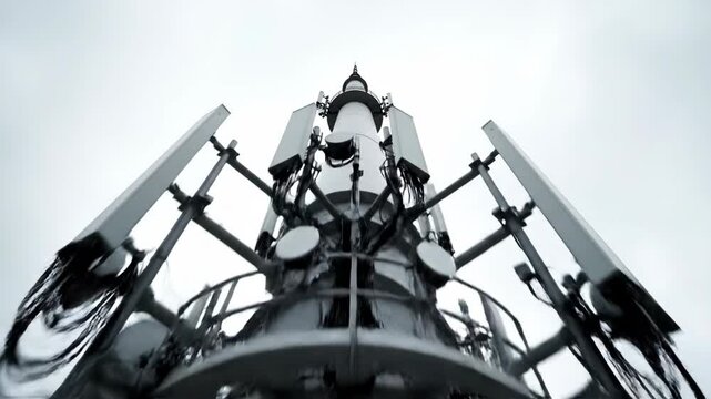 Modern white 5G telecommunications tower viewed from below against cloudy sky. Sequence shows tower structure from base to antennas. Wireless network infrastructure for high-speed internet
