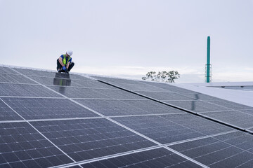 Engineers install solar panels on a wet rooftop during cloudy weather