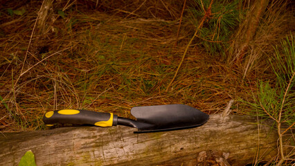 handheld garden shovel on a log in an autumn forest planting tool
