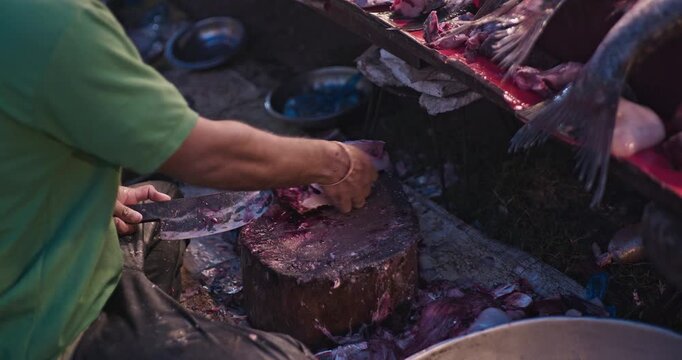 Fish market vendor cutting fresh fish for customers in a busy seafood market