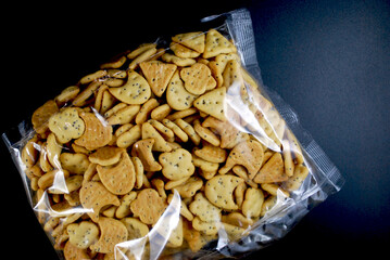 transparent package of small crackers with poppy seeds on a black surface
