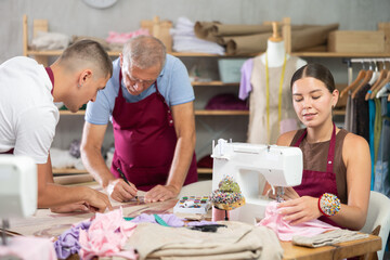 Family business, production of clothes - tailor showroom.Girl employee works with sewing machine...
