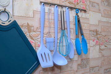 set of kitchen utensils and blue cutting board on the wall