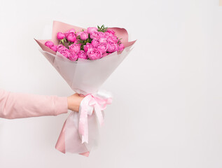 Elegant bouquet of pink peony roses held in a hand against a clean background