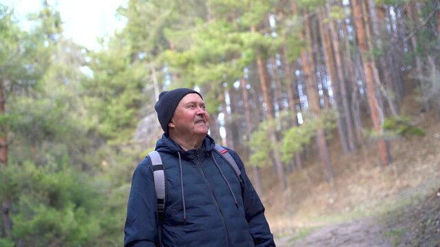 Happy senior man smiling while looking at forest during autumn hike