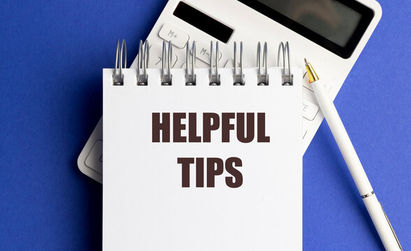 Notebook with text helpful tips on white paper with calculator and pen on blue background
