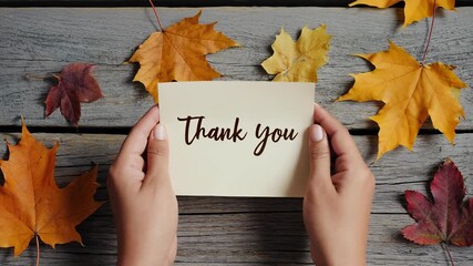 Holding a Thank You Note Surrounded by Autumn Leaves on Rustic Wood Table - Powered by Adobe