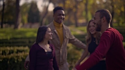 A heartwarming moment of four diverse young friends embracing and laughing together outdoors. This scene evokes feelings of happiness, connection, and true friendship in a natural environment.