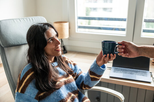 Latin woman receiving coffee while working from home - Powered by Adobe