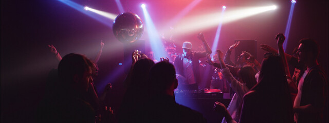 Vibrant dance party with DJ and lively crowd celebrating at night in colorful lighting