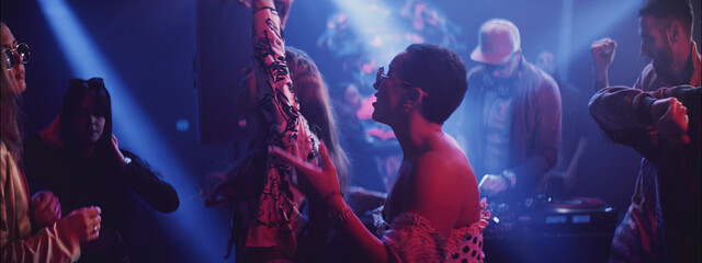 Vibrant nightclub scene with people dancing and enjoying live music in a colorful atmosphere