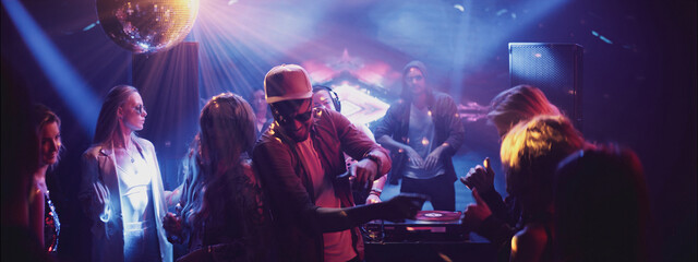 Party atmosphere in a club with a DJ, vibrant lights, and dancing guests during an exciting evening event