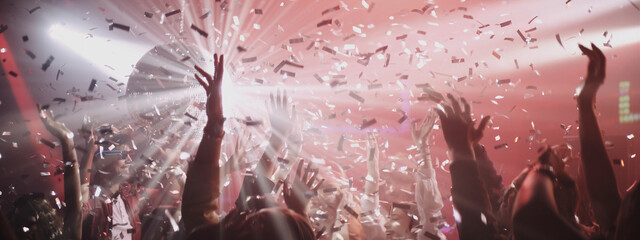 Wild celebration with colorful confetti and energetic crowd dancing at a lively party in the city at night
