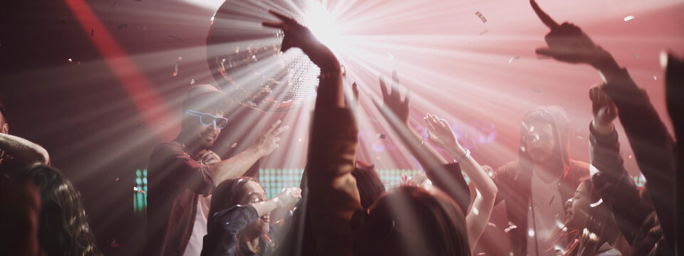 Dancers celebrate under colorful lights at a lively nightclub during a weekend party late at night