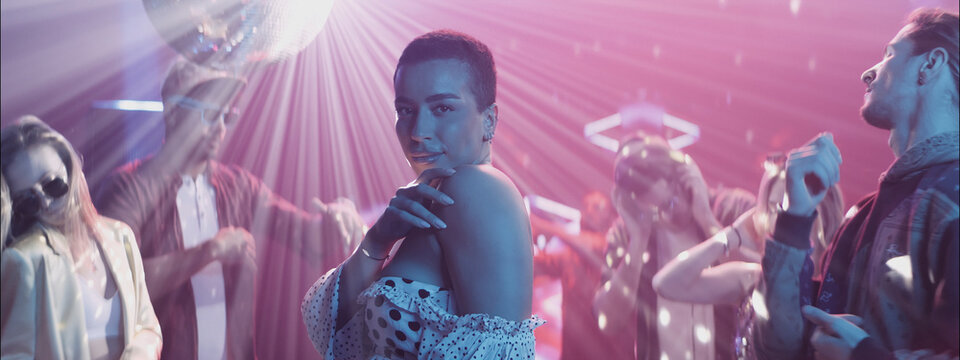 People dancing at a vibrant party with colorful lights and a disco ball in a lively club atmosphere in the evening