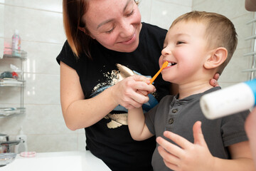 Mom helping to kids brush their teeth. Happy family