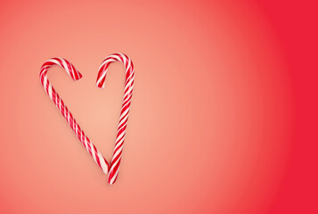 Two candy canes are positioned to form a heart shape against a bright red background. This festive design adds a cheerful touch to winter celebrations and holiday decorations.