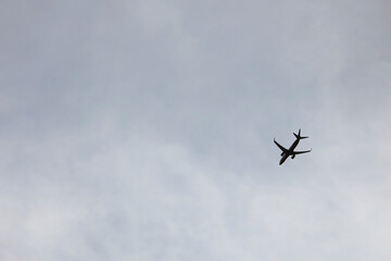 A Lone Plane Captured From Below Against An Overcast Sky. Concept Of Air Travel, Transportation, And Freedom.