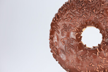 Macro Texture Of A Fresh Doughnut Topped With Dark Icing And Brown Sprinkles. A Sweet Dessert Concept.
