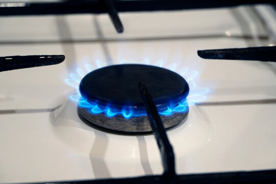 A close-up of a gas stove burner with a blue flame
