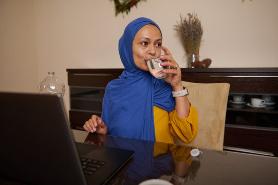 Professional Muslim Woman in Hijab Drinking Water During Work From Home Setting